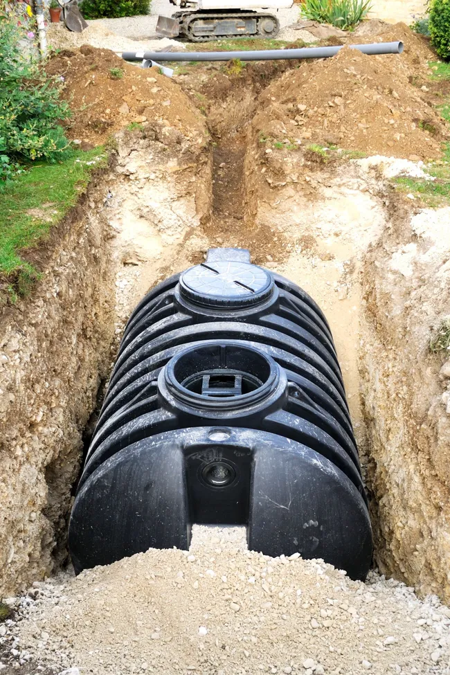 Black water tank being installed in a trench.
